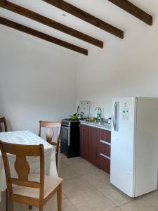 uma cozinha com um frigorífico branco, uma mesa e cadeiras em Casa los Boldos em Curacaví