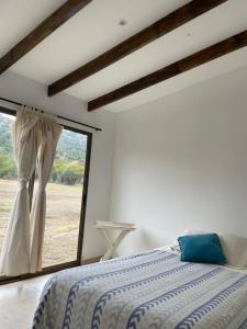 um quarto com uma cama e uma grande janela em Casa los Boldos em Curacaví