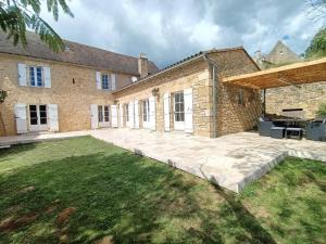 a large brick house with a large patio at Maison en pierre avec piscine in Lavergne