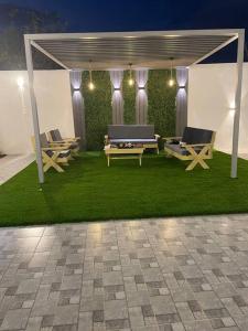 un cenador con bancos y mesas sobre hierba en شاليه راقي بمسطحات خضراء وغرفة نوم, en Qufār