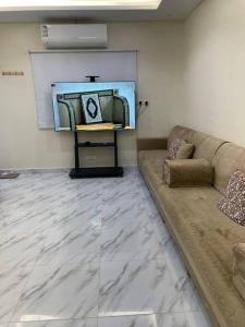 una sala de estar con sofá y una pintura en la pared en شاليه راقي بمسطحات خضراء وغرفة نوم, en Qufār