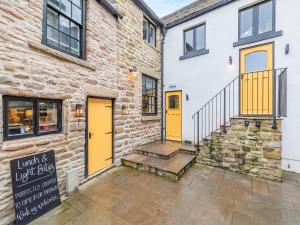 a brick building with yellow doors and a staircase at Deacons Apartment - Uk45211 in Chapel en le Frith