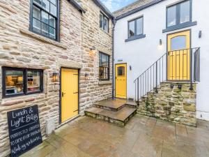 a brick building with yellow doors and a staircase at Deacons Apartment 2 - Uk45212 in Chapel en le Frith