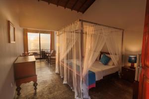 a bedroom with a canopy bed with a view of the ocean at Hotel Zeilan Sunset Point in Unawatuna