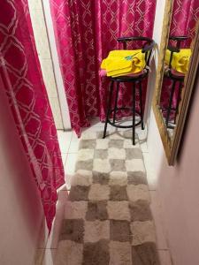 a hallway with a bar stool and pink curtains at Home In Gated Community 24Hr Security And Wifi in Old Harbour