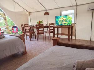 una habitación con mesa de comedor y TV en una tienda de campaña en Volcano Tenorio Glamping Ranch - 3 Tents, en Rio Celeste