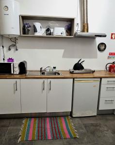 a kitchen with white cabinets and a sink and a rug at AL - Studio to Travelers in Ponta Delgada
