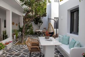 un patio con mesa, sillas y un árbol en Juliano luxury apartments, port of Naxos, en Naxos Chora