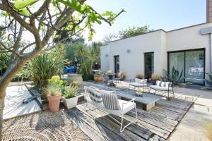 eine Terrasse mit Stühlen, Tischen und Pflanzen in der Unterkunft Maison contemporaine avec jardin près de la plage in La Baule