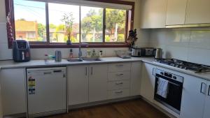 a kitchen with white cabinets and a sink and a window at Clayton Living Town House at Monash Doorstep in Clayton North