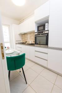 a kitchen with white cabinets and a green chair at Suit apartment free parking in Roşu