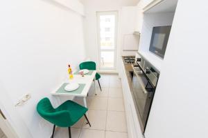 a small kitchen with a white table and green chairs at Suit apartment free parking in Roşu +3 photos