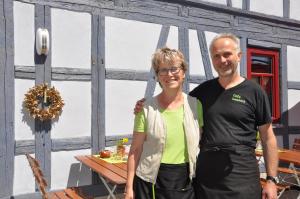 Ein Mann und eine Frau stehen vor einem Tisch. in der Unterkunft Café Landart im Thüringer Finistère in Plaue