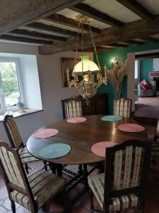 une table à manger avec des chaises et un lustre dans l'établissement Gîte l’Aubépine, à Les Hautes-Rivières