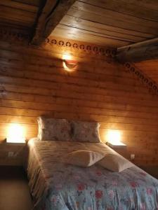 - une chambre avec des murs en bois et un lit avec deux lumières dans l'établissement Gîte l’Aubépine, à Les Hautes-Rivières