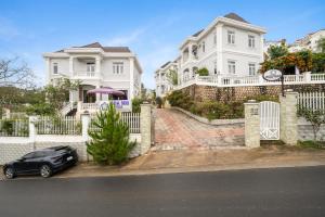 een zwarte auto geparkeerd voor witte huizen bij Myrtle Boutique Hotel in Da Lat