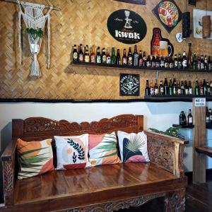 un banco de madera en un bar con botellas en la pared en Hidden of Cailan Extension Transient House, en El Nido