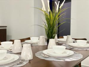une table avec des tasses et des soucoupes blanches dans l'établissement Mayura Accomodation, à Kuala Lumpur