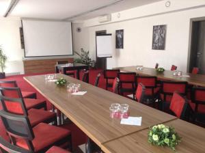 a conference room with wooden tables and red chairs at Hotel Monde in Uherský Brod