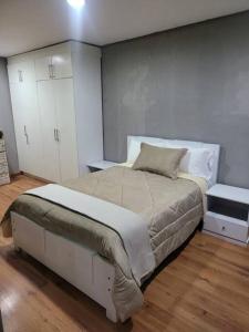 a bedroom with a large bed and white cabinets at hermosa casa en cuenca in Cuenca