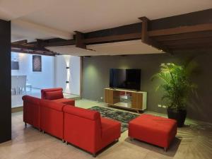 sala de estar con muebles de color rojo y TV de pantalla plana en hermosa casa en cuenca, en Cuenca