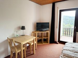 a room with a table and a television and a bed at Schwarzwaldblick in Triberg