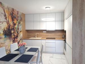 a kitchen with white cabinets and a table with chairs at Tabáň Luxury apartment (city center & free parking) in Nitra