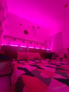a bedroom with pink lights on a bed at RDTROOM At Aeropolis in Teko