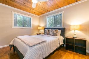 um quarto com uma cama com 2 candeeiros e 2 janelas em Hidden Willow at Tahoe Park - Cozy 2 BR Cabin, Walk to Dining, Near Skiing em Tahoe City