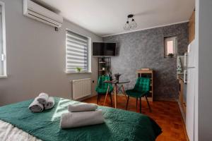 a bedroom with a bed and a table and green chairs at Dream Inn apartments in Subotica