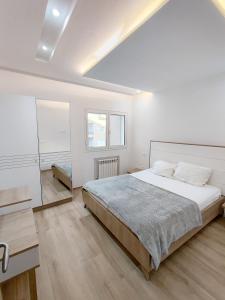 una camera bianca con un grande letto e uno specchio di Superbe appartement la Terrasse Hammamet Nord Mrezga a Hammamet