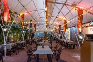 a restaurant with tables and chairs and lights at La Ben Resort in Colva