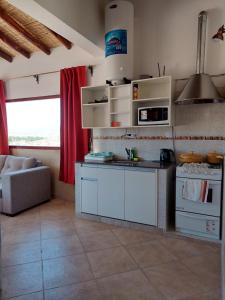 uma cozinha com armários brancos e um sofá num quarto em Puertas del Cielo II em Cachí