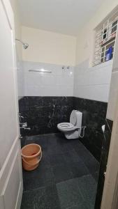 a bathroom with a toilet and a black tile floor at Kamalam 2 BHK - Non AC in Coimbatore