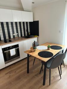 uma cozinha com uma mesa de madeira e cadeiras numa cozinha em Katrine em Saint-Étienne