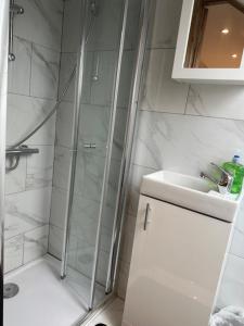 La salle de bains est pourvue d'une douche et d'un lavabo. dans l'établissement Luton Home near Airport Private & Shared Bathroom Option, à Luton