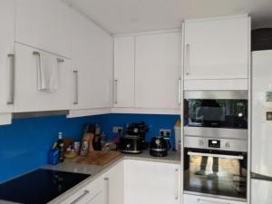 a kitchen with white cabinets and a stove top oven at Central and peaceful room with your own bathroom in London