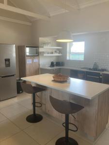 a kitchen with a large island with two bar stools at Blessed at Ten76 holiday home in Witsand in Witsand