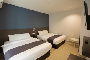 a hotel room with two beds and a television at 1 Hotel Signature in Port Dickson