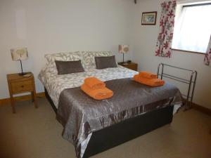 ein Schlafzimmer mit einem Bett mit zwei orangenen Handtüchern darauf in der Unterkunft Withersdale Cross Cottages in Mendham