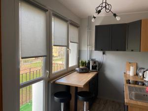 a kitchen with windows and a wooden counter with stools at Broniewskiego Centrum Konin in Konin