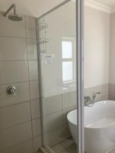 y baño con ducha, bañera y lavamanos. en Blessed at Ten76 holiday home in Witsand, en Witsand