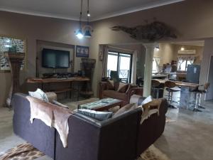 uma sala de estar com um sofá, uma mesa e uma televisão em Kichaka Nyumba em Marloth Park