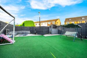 a backyard with an artificial turf soccer field at 3 Bed Family House in Solihull ☆ LARGE GARDEN & FREE PARKING ✪ BY (BHX) Birmingham Airport → (NEC) National Exhibition Centre, Resorts World Birmingham, Jaguar Land Rover Solihull - BY PILOT MY PROPERTY ® in Water Orton