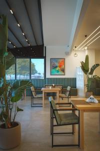 a waiting room with tables and chairs and plants at Sea & Sand Hotel in Vlorë