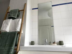 a bathroom with a sink and a mirror and towels at Maison de ville - près de LILLE in Mouvaux