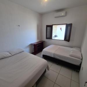 a hotel room with two beds and a television at Casa Camocim in Camocim