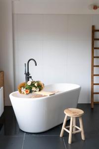 a white bath tub with a faucet and a stool at Urban Hotel The Golden Stork in Rijswijk