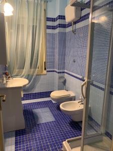 Un baño con azulejos azules, inodoro y lavabo. en Domus Diocleziano, en Nápoles