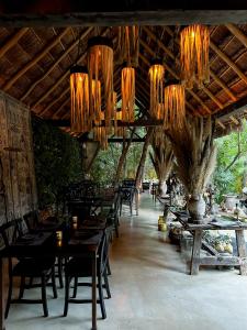 a restaurant with wooden tables and chairs and chandeliers at Hotel Bardo - Adults Only in Tulum